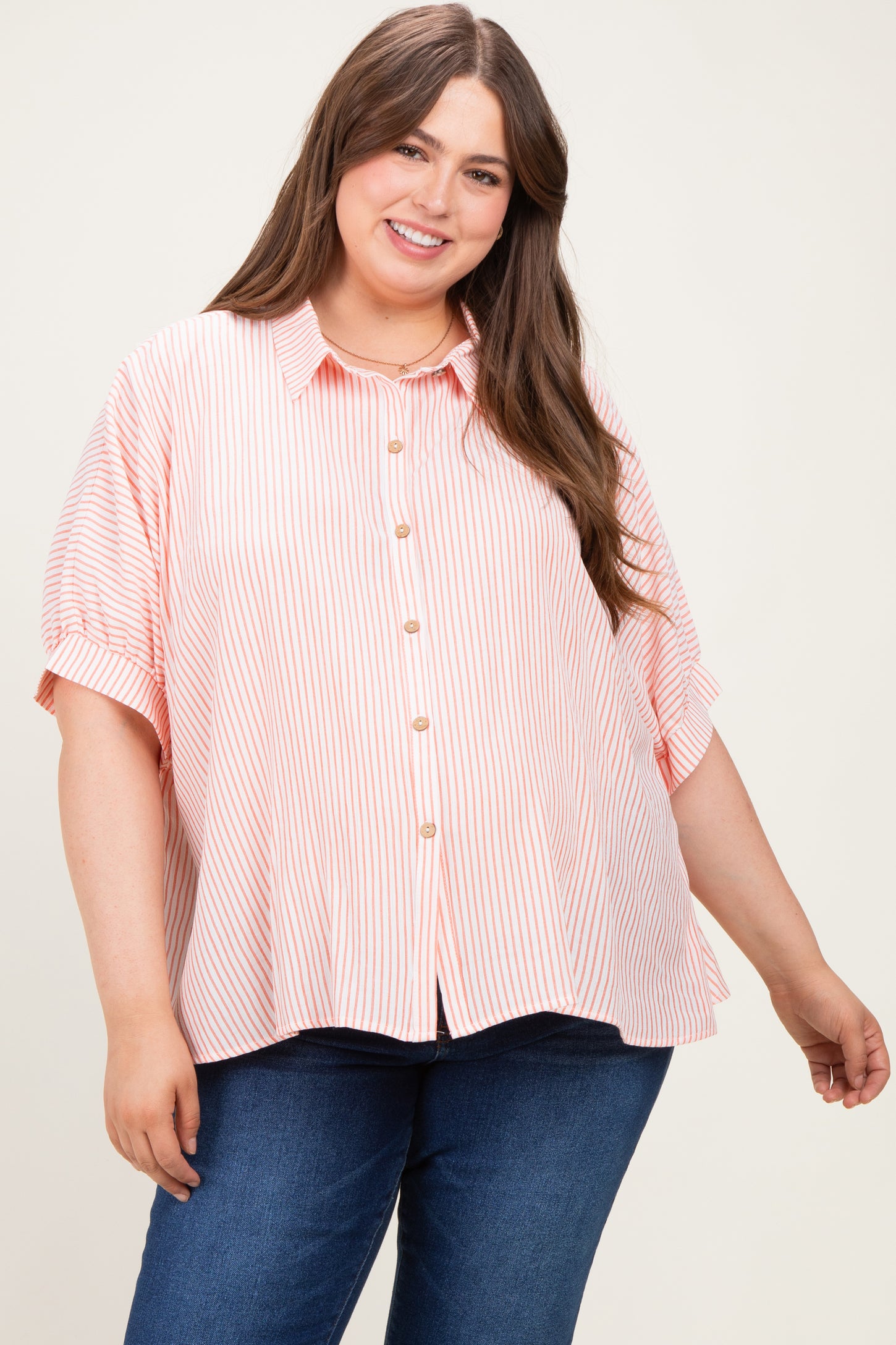 woman wearing a pink and white striped maternity button-up shirt with a relaxed fit and short sleeves