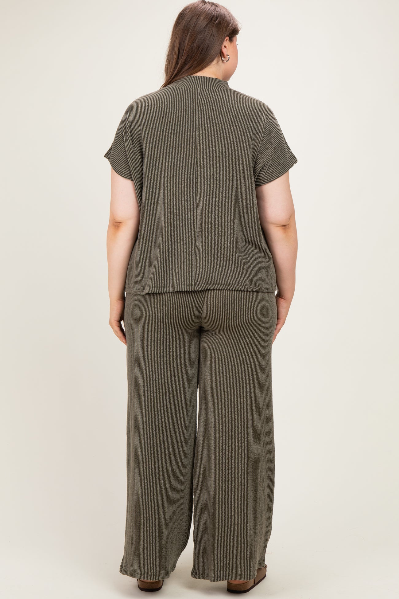 woman wearing an olive green striped maternity plus lounge set, showing the back view of the top and wide-leg pants