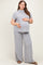 woman wearing a striped light gray maternity top and matching wide-leg pants, gently holding her baby bump