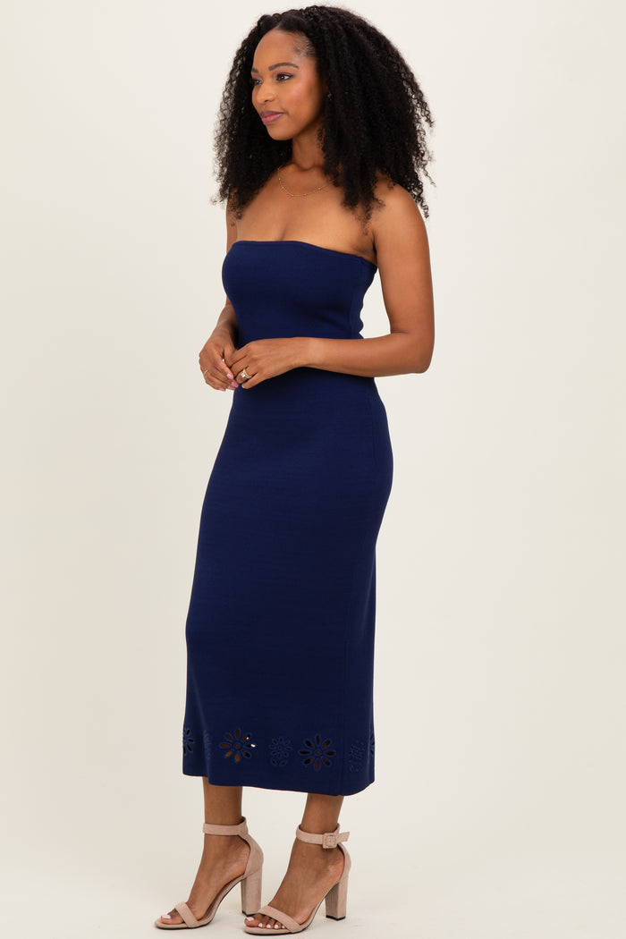 woman wearing a navy strapless midi dress with embroidered floral details at the hem and nude high-heeled sandals