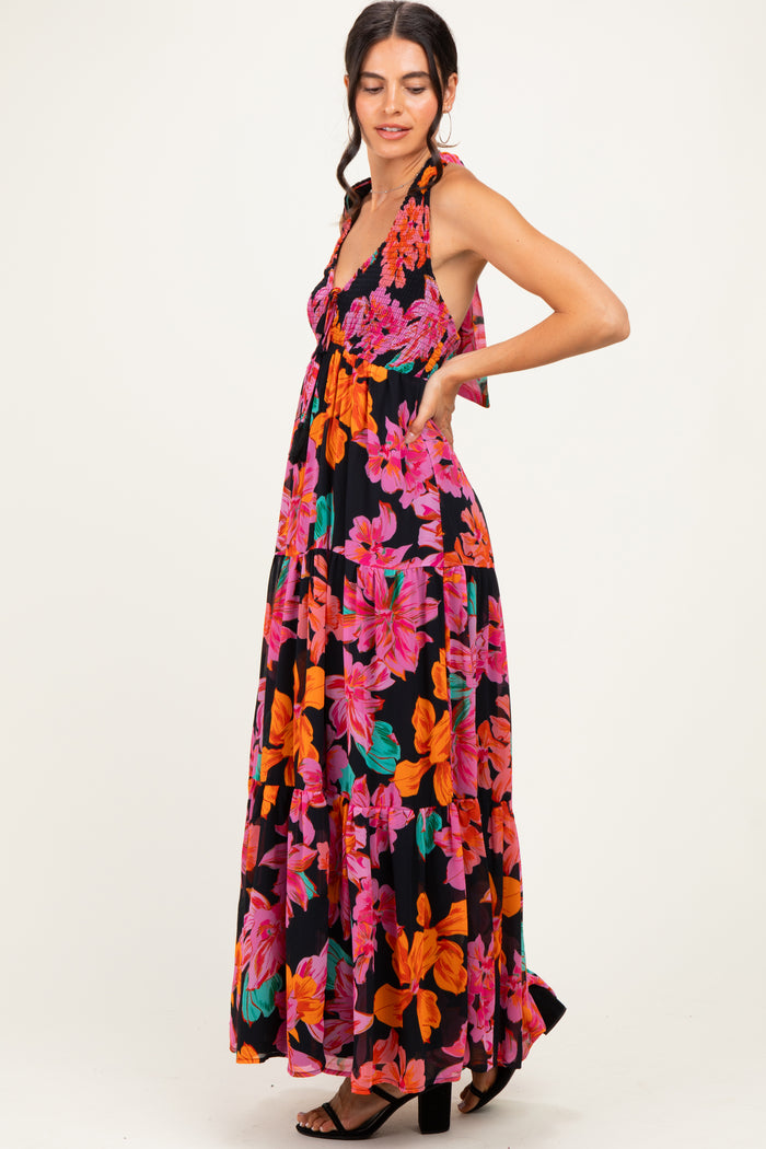 woman wearing a black floral maxi dress with a halter neck and vibrant pink and orange flowers