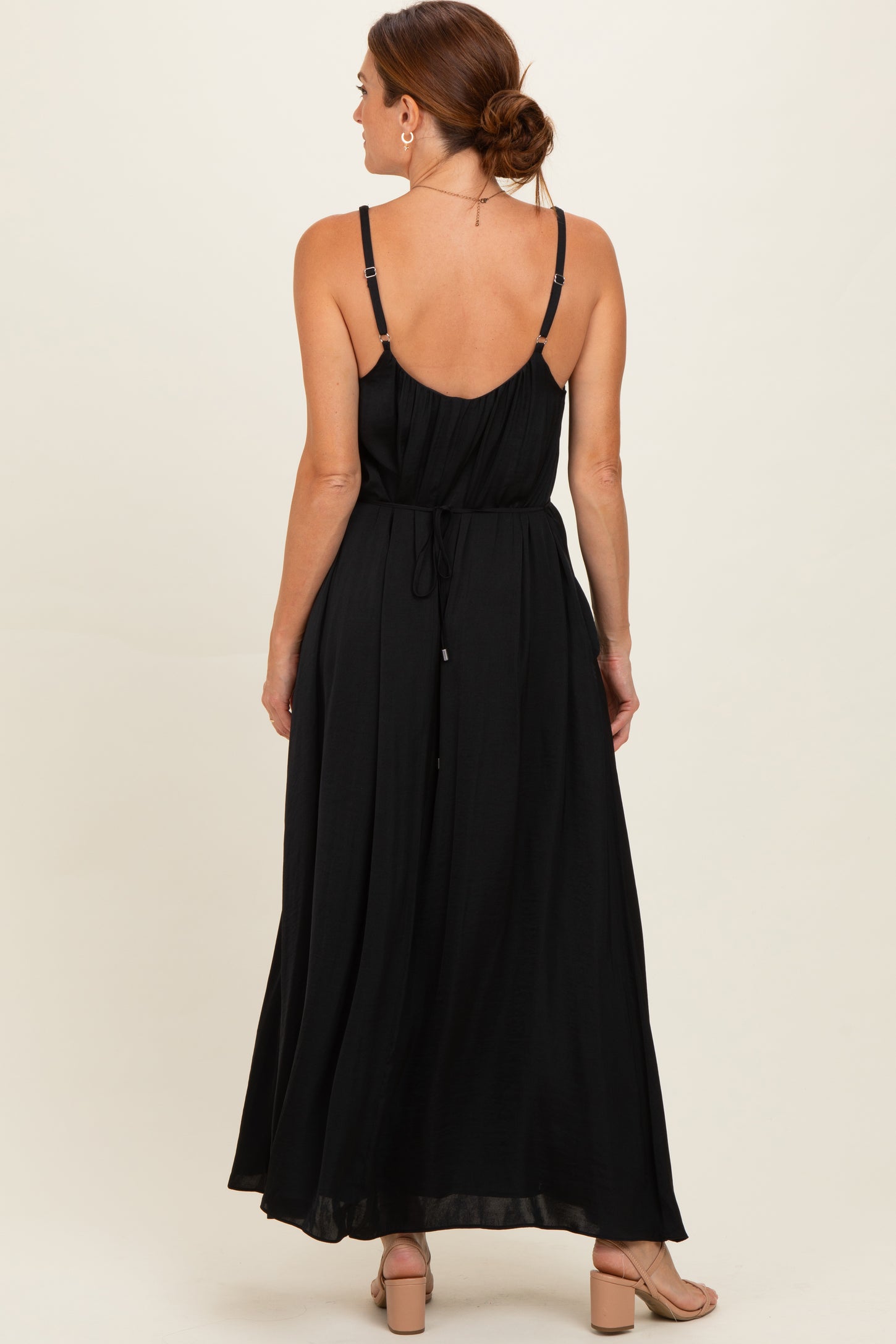 woman wearing a black maxi dress with spaghetti straps and a cinched waist, shown from the back