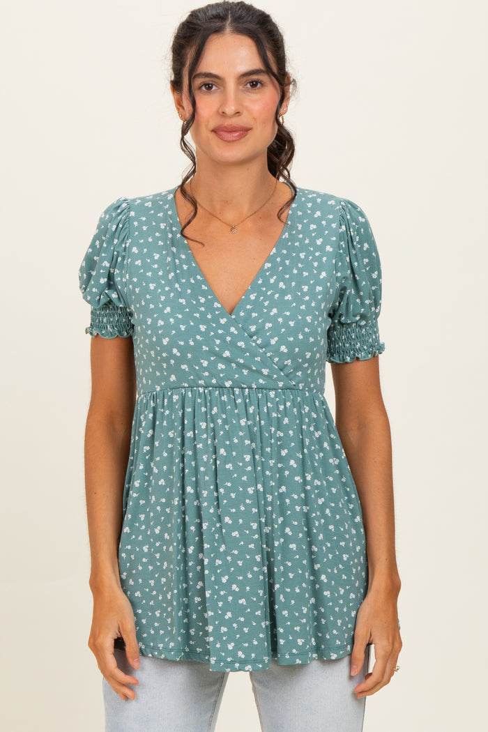 woman wearing a teal floral print short sleeve wrap top with puff sleeves and a gathered waist