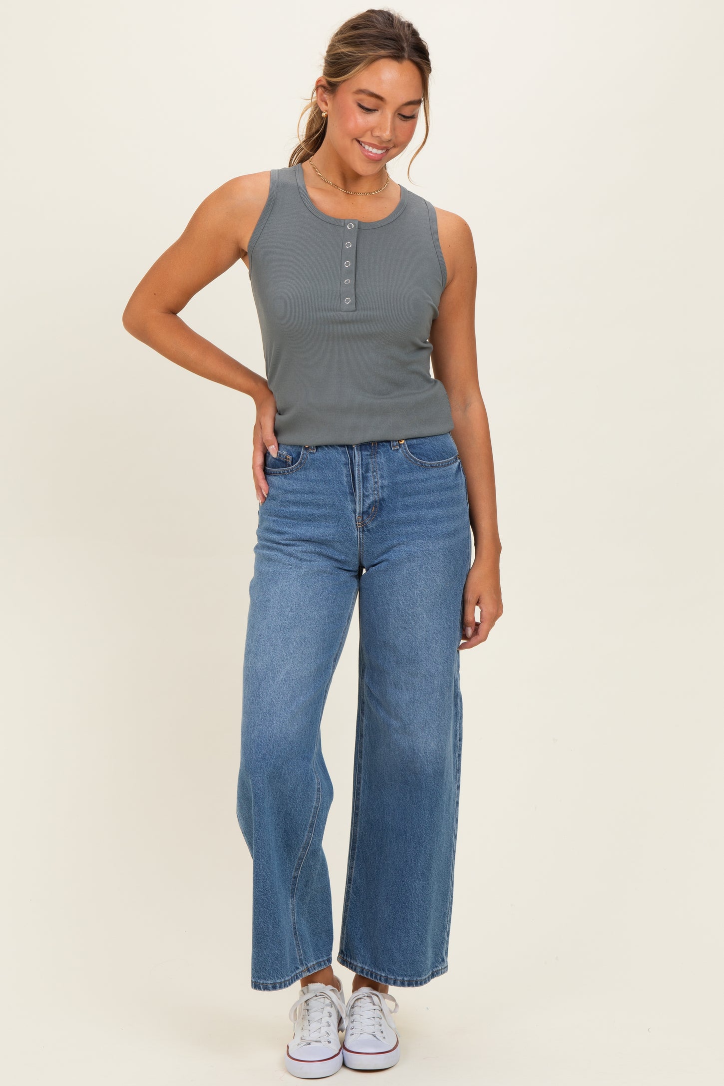 woman wearing a gray ribbed tank top with button details and high-waisted blue wide-leg jeans