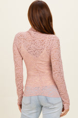 woman wearing a light mauve long sleeve lace top with a fitted silhouette and a sheer back detail
