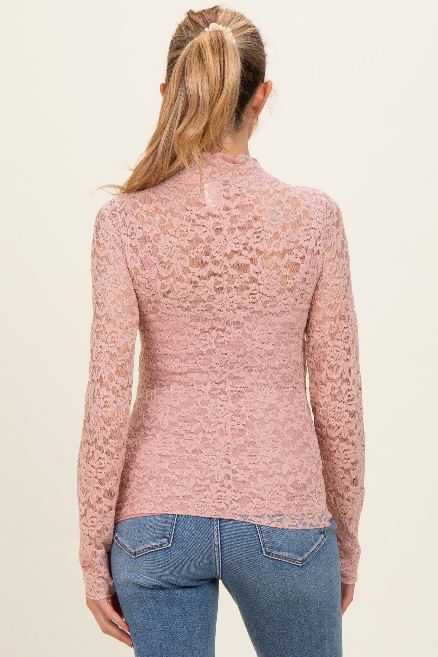 woman wearing a dusty pink lace maternity top with long sleeves and sheer back detail