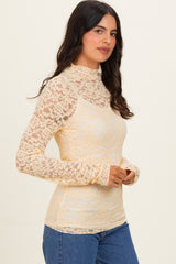 woman wearing a cream lace long sleeve top with a mock neck and fitted style, paired with blue jeans
