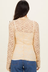 back view of a woman wearing a sheer yellow lace long sleeve top over a fitted bodice with a casual style