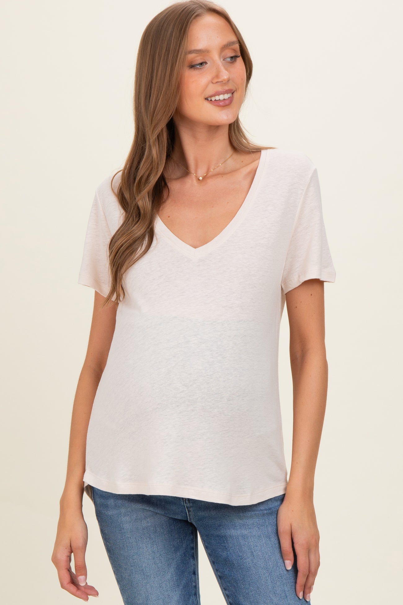 woman wearing a light pink v-neck maternity top with short sleeves and a baby bump visible