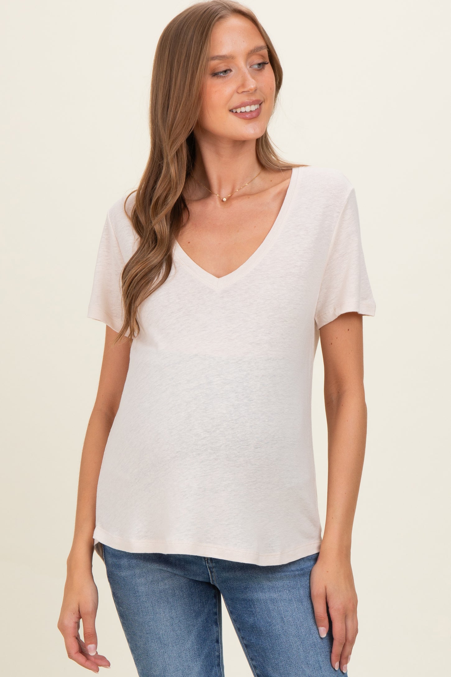 woman wearing a light pink v-neck maternity top with short sleeves and a baby bump visible