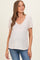 woman wearing a light pink v-neck maternity top with short sleeves and a baby bump visible