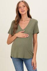 woman wearing an olive green short sleeve maternity top and holding her baby bump