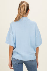 woman wearing a light blue short sleeve maternity sweater, showing a relaxed fit and ribbed hem