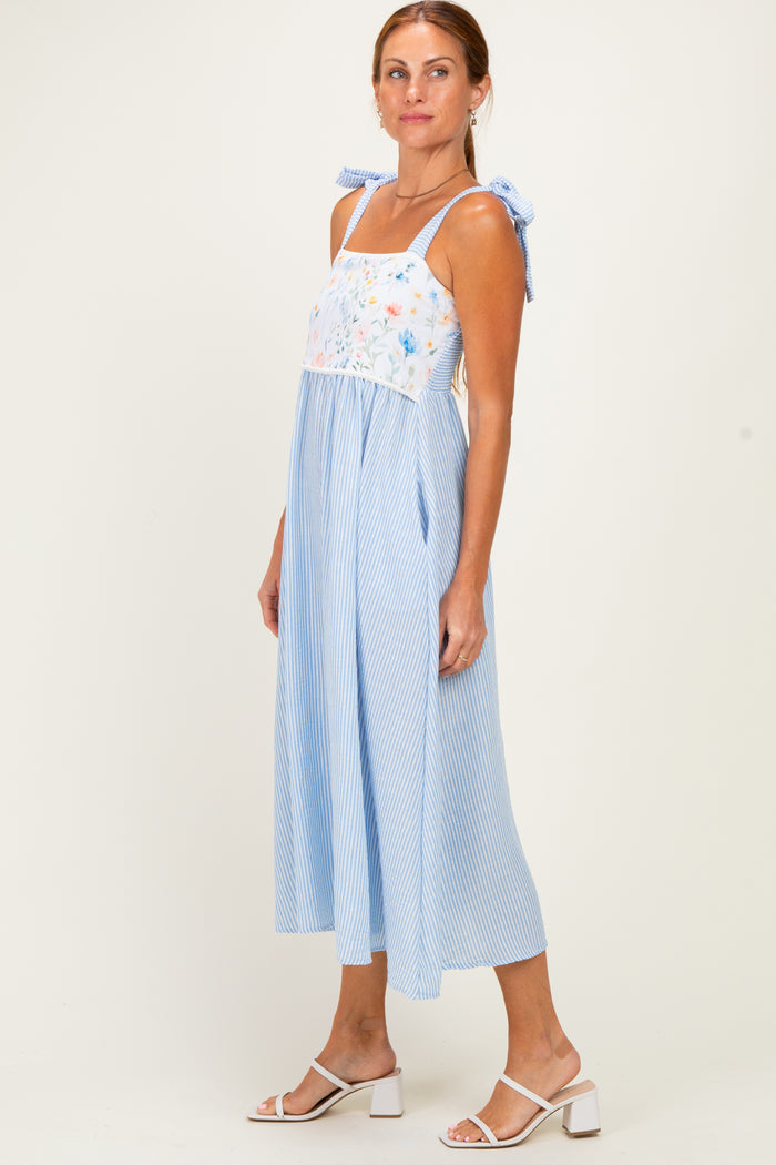 woman wearing a blue and white striped midi dress with floral embroidery and adjustable shoulder ties