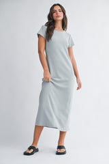 woman wearing a light gray short sleeve maxi dress and black sandals