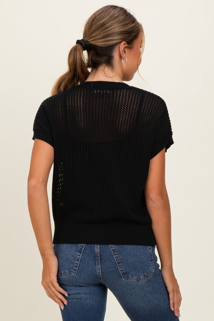 woman wearing a black short sleeve knitted sweater with a loose fit, shown from the back with blue jeans