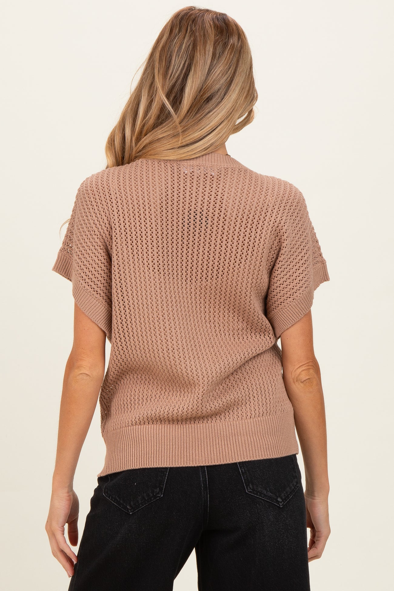 woman wearing a beige knit maternity sweater with short sleeves, shown from the back