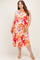 woman wearing a floral midi dress with halter neck and tie waist, showcasing her baby bump in maternity plus size