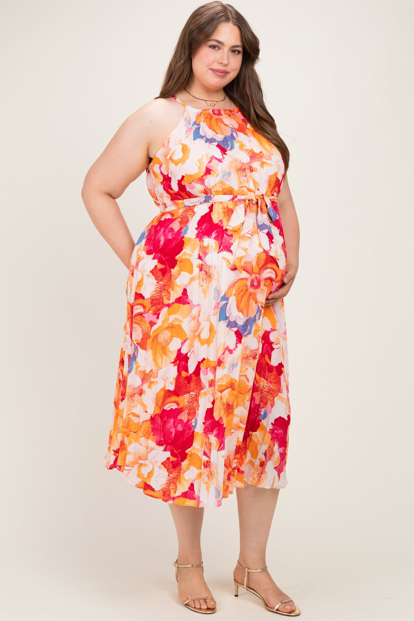 woman wearing a floral maternity plus dress with an empire waist and pockets, showcasing her baby bump