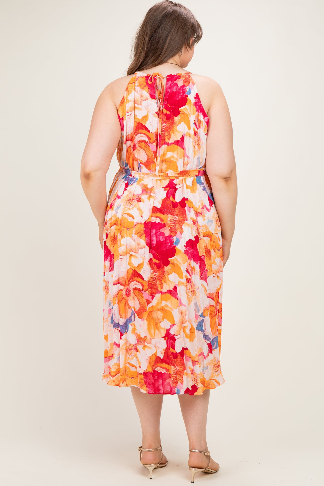 woman wearing a floral midi maternity dress with a tie-back detailing and a flowing silhouette, view from the back