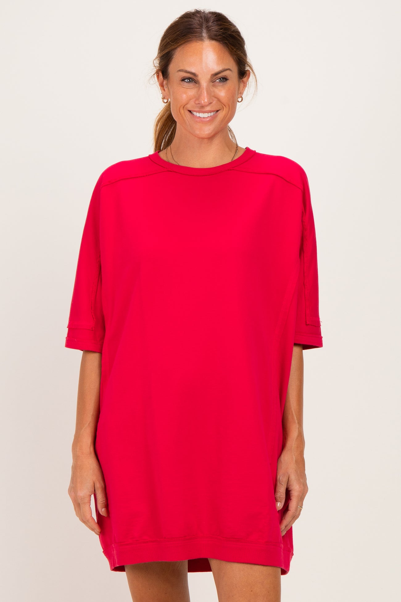 woman wearing a bright red oversized t-shirt dress with short sleeves and a relaxed fit