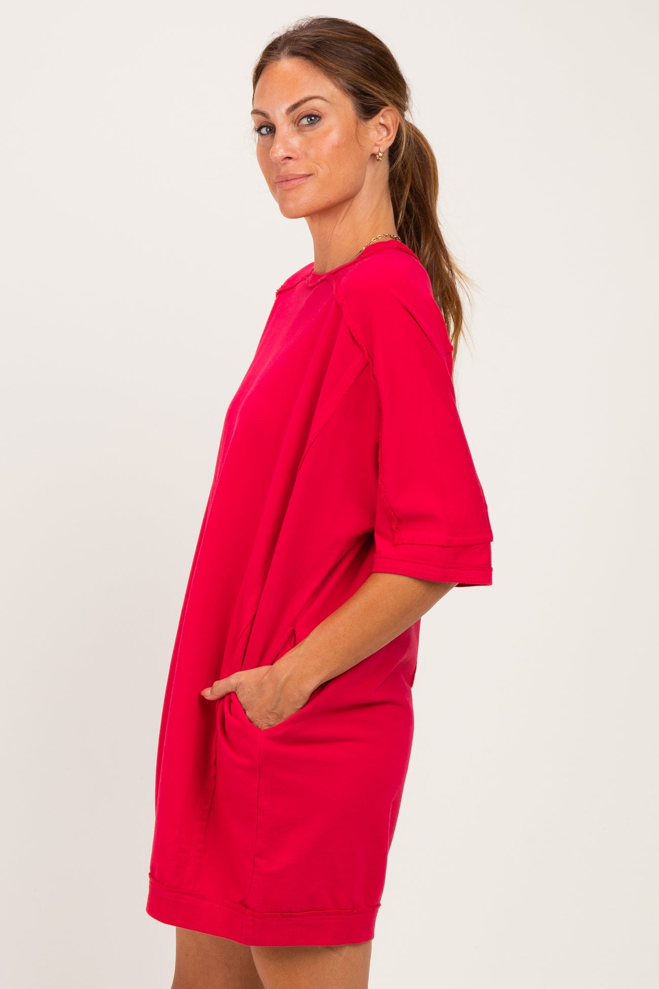 woman wearing a bright pink short sleeve dress with pockets, styled in a relaxed silhouette