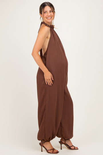 woman wearing a brown maternity jumpsuit with a halter neck and a visible baby bump