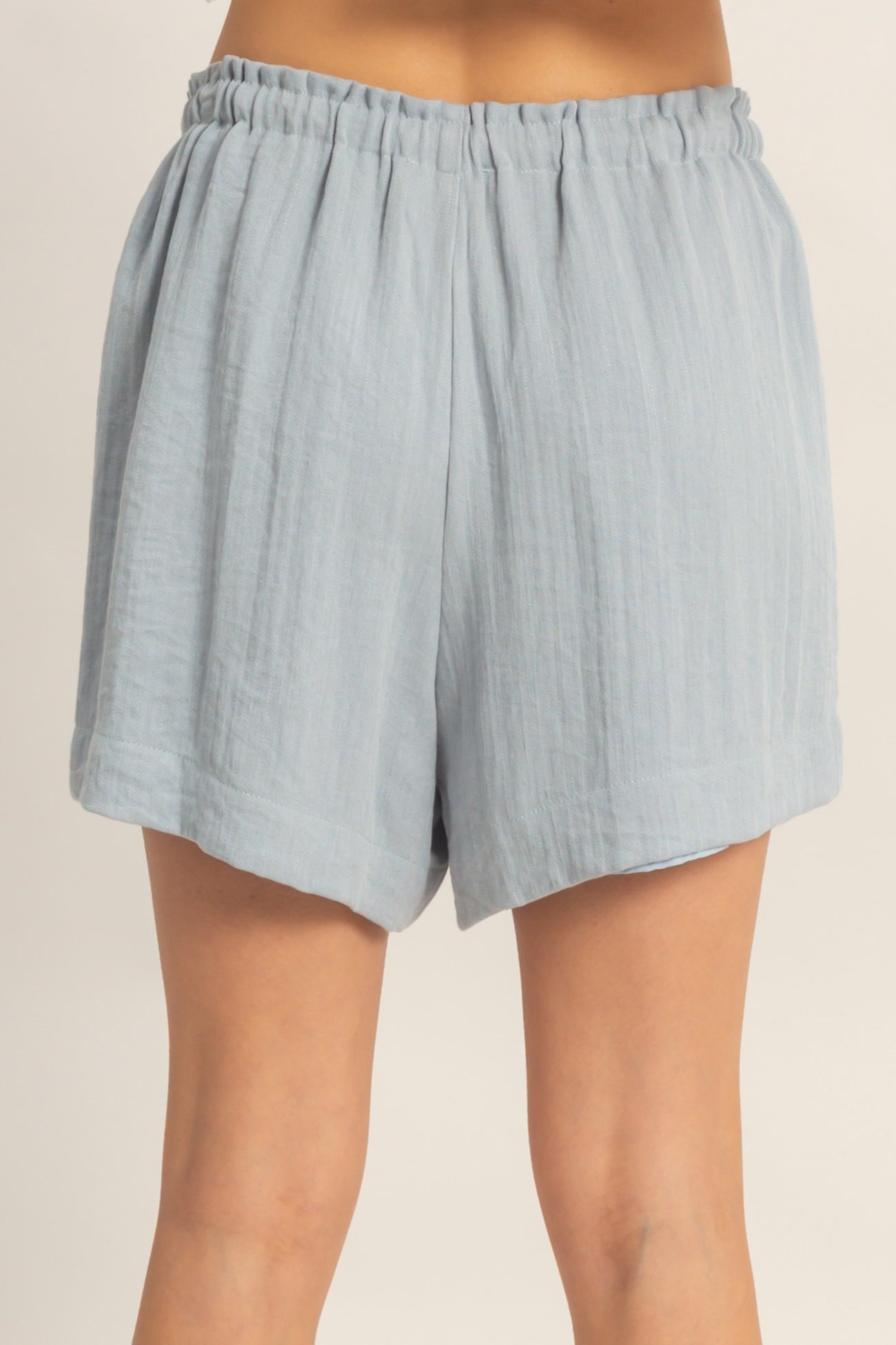 woman wearing light blue linen shorts with an elastic waistband and a relaxed fit