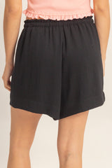 woman wearing black relaxed fit shorts with an elastic waistband and a split hem detail