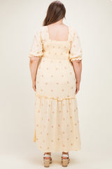 woman wearing a yellow floral maternity plus maxi dress with puff sleeves and a tiered skirt, showcasing a baby bump