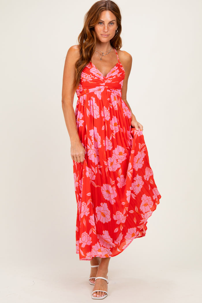 woman wearing a red maxi dress with pink floral print and a fitted bust, posing with one hand on her hip