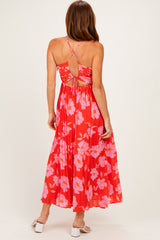 woman wearing a red floral maxi dress with a crisscross back design and pleated skirt