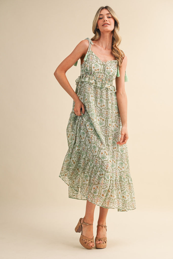 woman wearing a green and white floral maxi dress with adjustable straps and a ruffled hem