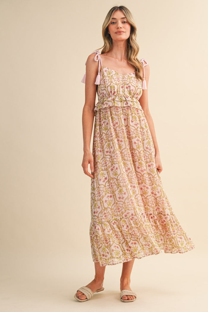 woman wearing a pink floral maxi dress with adjustable tie straps and a tiered skirt