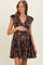 woman wearing a black floral maternity dress with short sleeves and a tiered skirt, holding her baby bump
