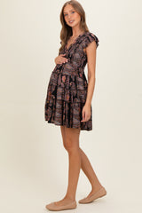 woman wearing a black floral maternity dress with ruffled sleeves and a baby bump visible