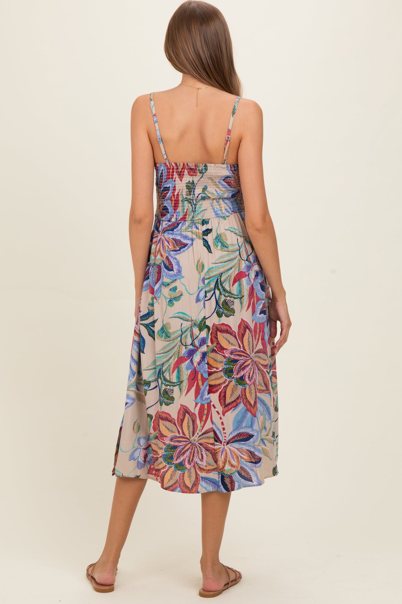 woman wearing a floral maternity dress with spaghetti straps and a smocked back, showing a colorful pattern