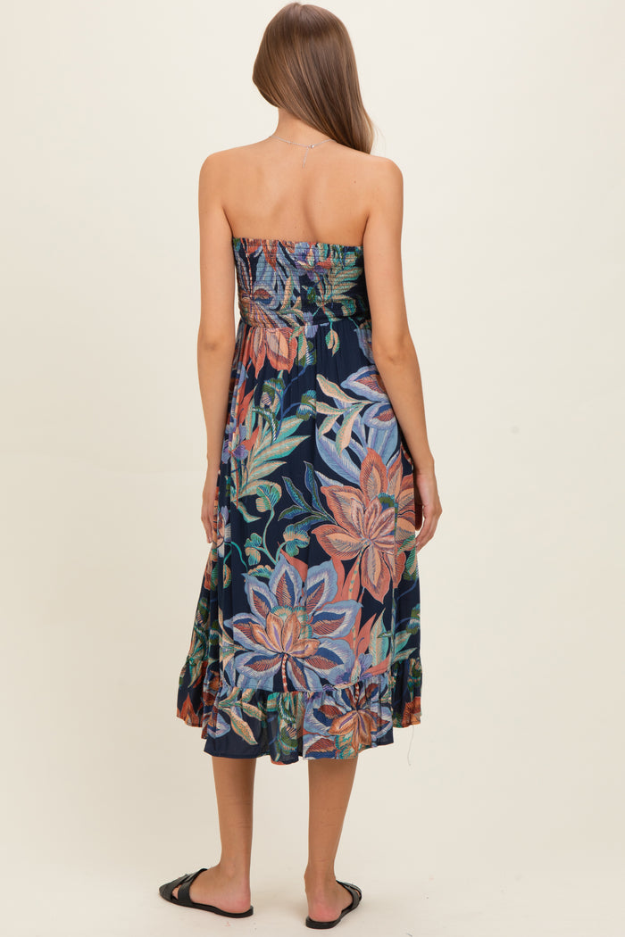woman wearing a colorful floral strapless maternity dress with a tiered hem, showing her baby bump from the back.