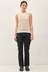 woman wearing a cream and orange striped sleeveless sweater with dark wash flared jeans and navy sneakers