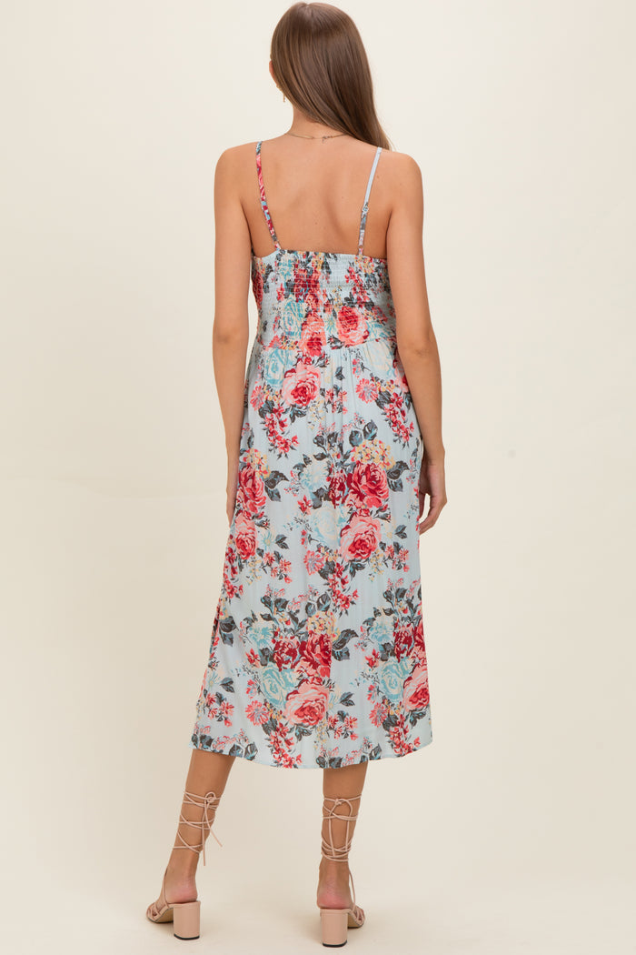woman wearing a floral print maternity dress with a smocked back and adjustable straps, featuring a mid-length flowy skirt
