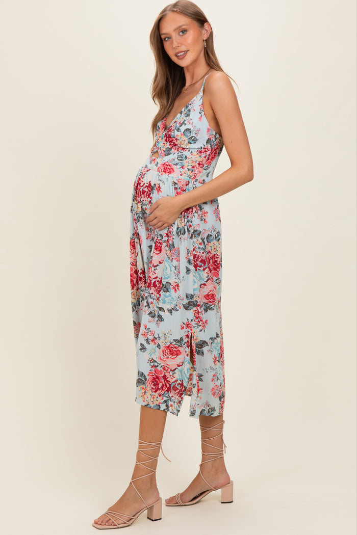 woman wearing a light blue floral maternity dress with a v-neckline and holding her baby bump