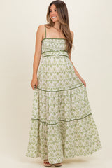 woman wearing a green and white floral maternity maxi dress with a belted waist and tiered skirt