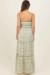 woman wearing a green and white floral maternity maxi dress with a tiered design and spaghetti straps