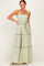 woman wearing a green and white floral maxi dress with smocked bodice and tiered skirt, posing with one hand on her hip