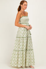woman wearing a green and white floral maxi dress with spaghetti straps and a fitted bodice, standing in profile