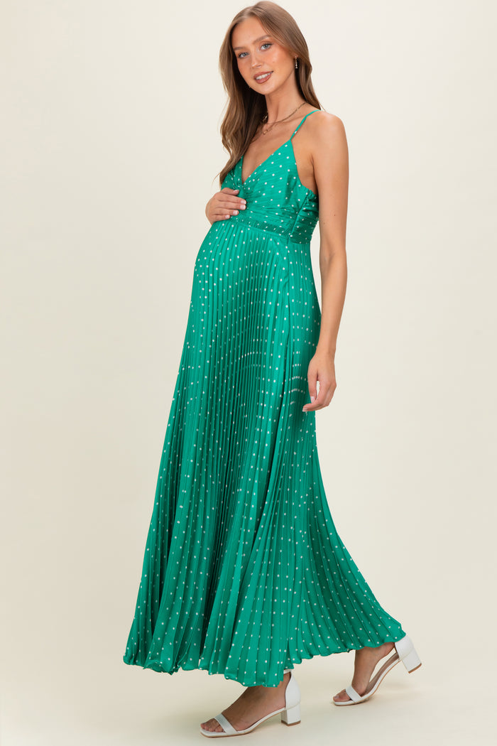 woman wearing a green pleated maternity dress with white polka dots and a visible baby bump