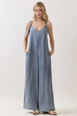 woman wearing a light blue denim jumpsuit with tie straps and side pockets