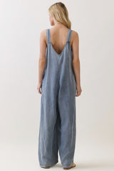 woman wearing a backless light blue denim overall jumpsuit with wide leg style