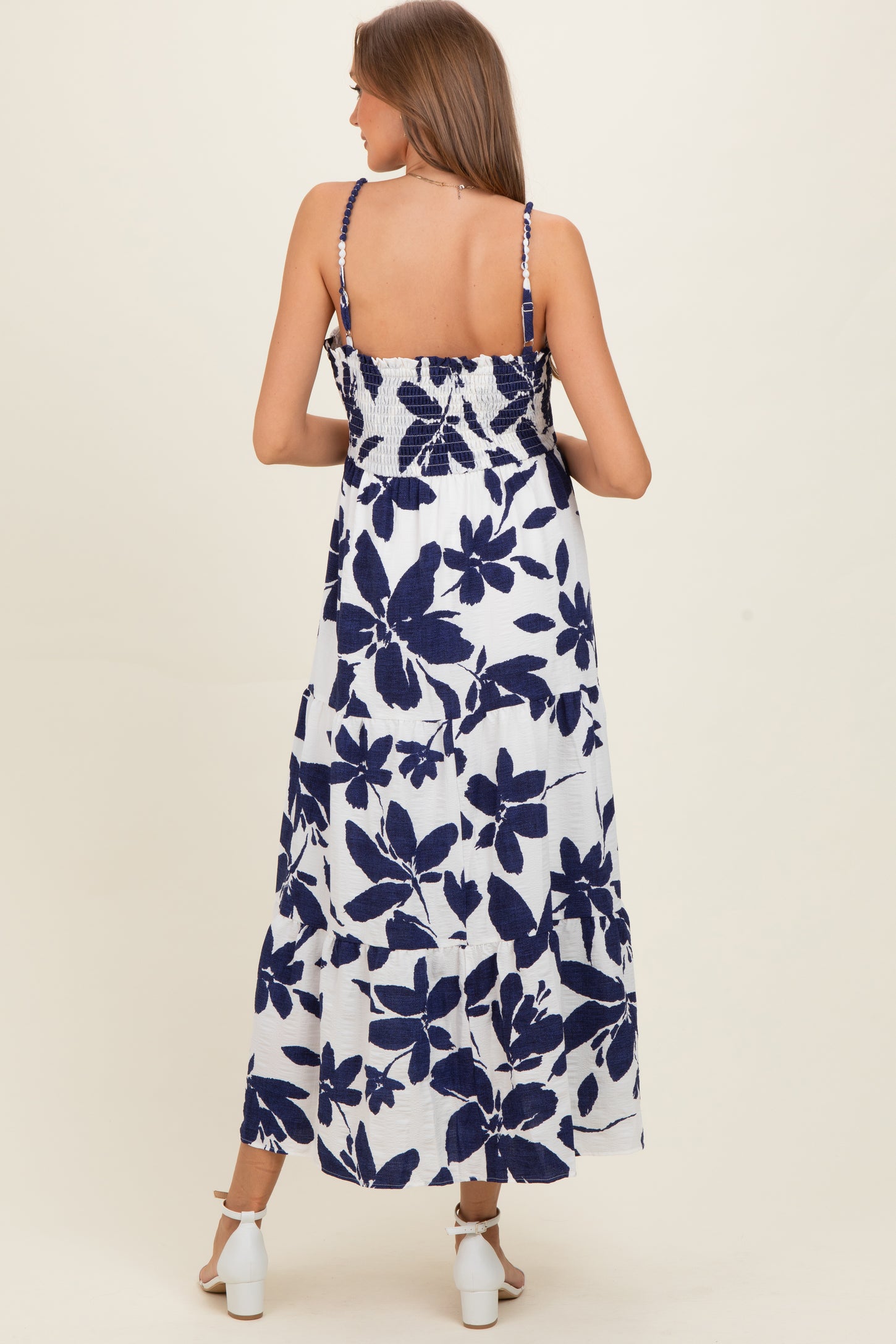 woman wearing a navy and white floral print maternity maxi dress with smocked back and adjustable straps