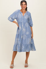 woman wearing a blue midi dress with floral print and balloon sleeves, standing in a relaxed pose
